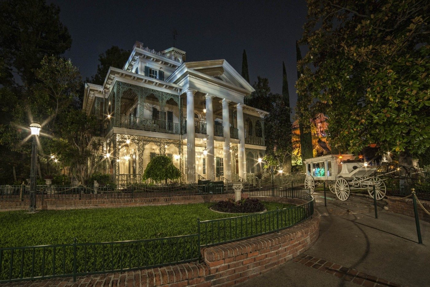 The mansion lit at night beside its front lawn