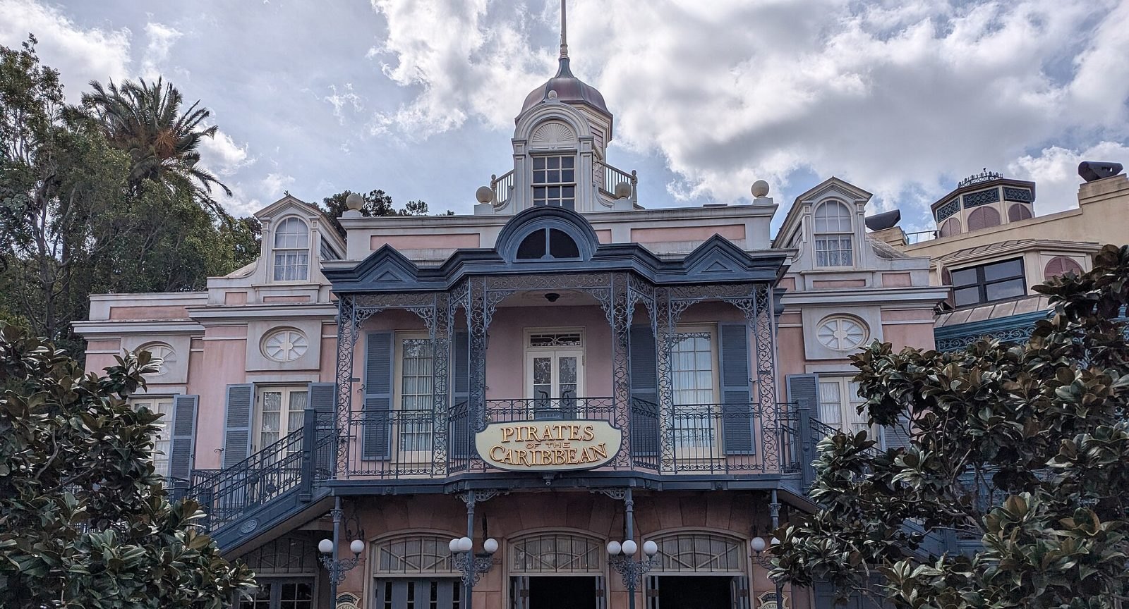 The entrance building with its cupola and iron balconies under a cloudy sky